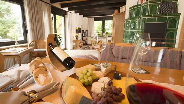 A dining table with cheese, grapes, wine, and bread.