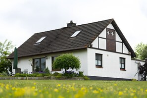Une maison avec un toit en pente, une cheminée et une fenêtre donnant sur le ciel.