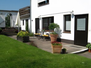 Une maison moderne dotée d’un patio, d’un espace salon extérieur et de plantes en pot.