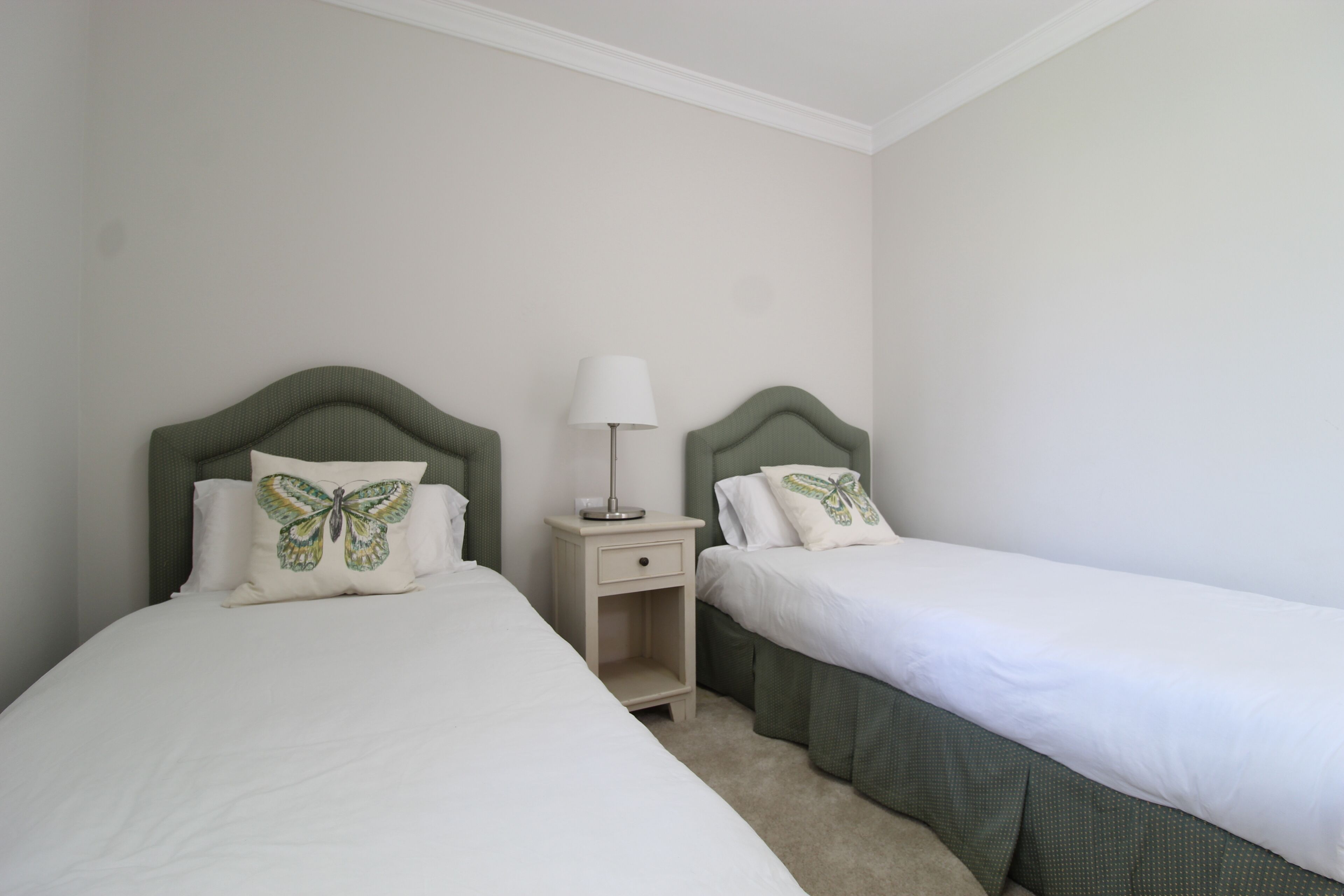 A twin room with two single beds, each with a headboard, a bedside table with a lamp, and a small drawer.