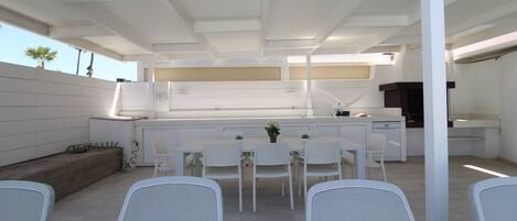 A modern outdoor kitchen with white furniture and a dining area.