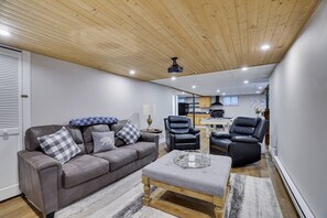 Un soggiorno moderno con un divano grigio, poltrone in pelle nera, un tavolino in legno e una ventola a soffitto.