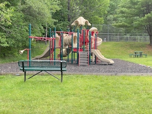 A playground with a slide, climbing structures, and a bench.