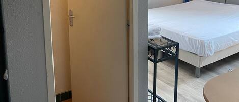 Una habitación de hotel con una cama, una mesita y una puerta que da a otra habitación.
