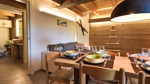 A wooden dining table set with plates, glasses, and cutlery. A wooden bench and a sofa with cushions are visible in the background. - Ai Tini by Interhome (Campodolcino)