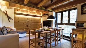 A cozy wooden interior with a dining area, a sofa, and a TV. - Ai Tini by Interhome (Campodolcino)