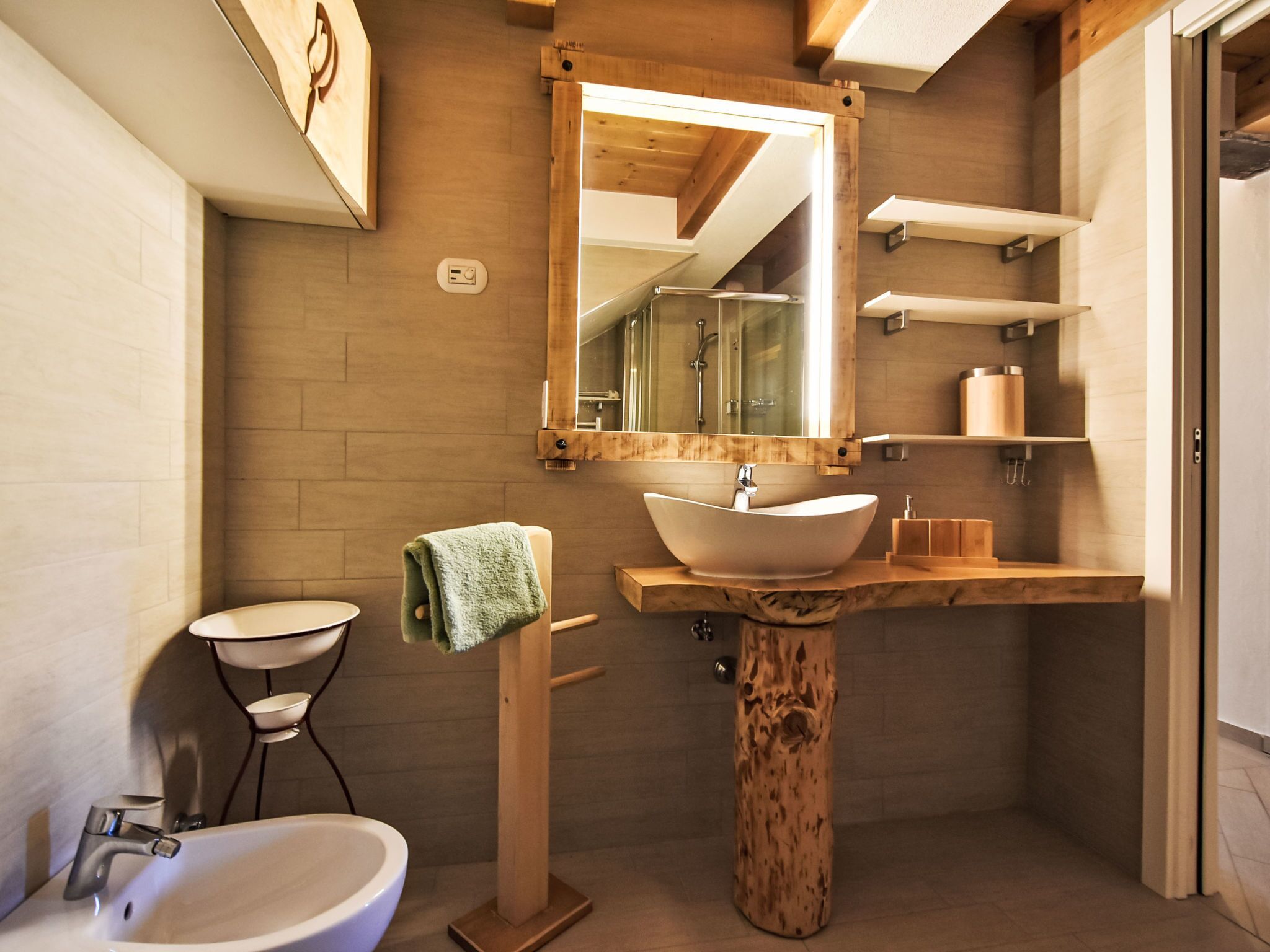 Une salle de bain moderne avec un meuble-lavabo en bois, un grand miroir, un lavabo, un bidet et un porte-serviettes.