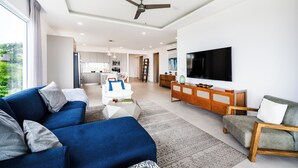 A modern living room with a blue sofa, a grey sofa, and a wooden cabinet with a TV.