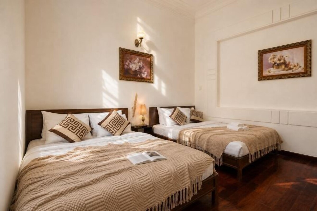 A hotel room with two beds, a nightstand, a lamp, and framed artwork on the walls.