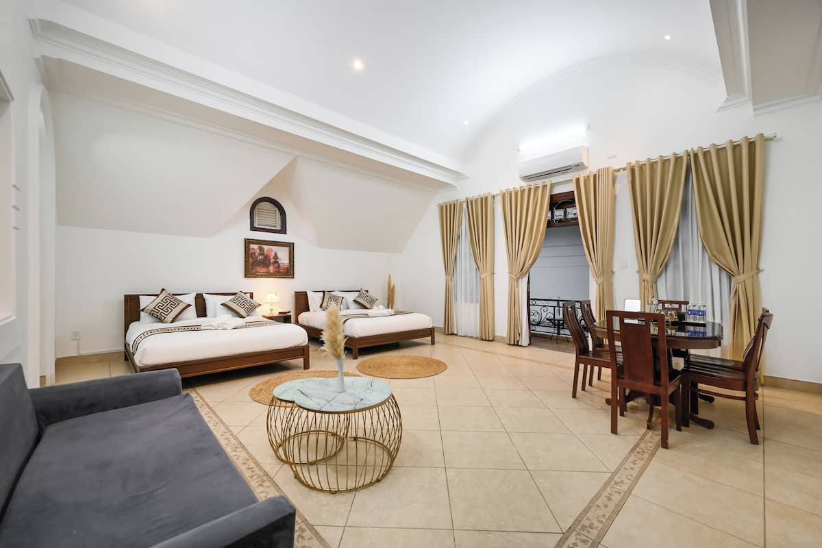 A spacious living room with a sofa set, a dining table with chairs, and a decorative round table.