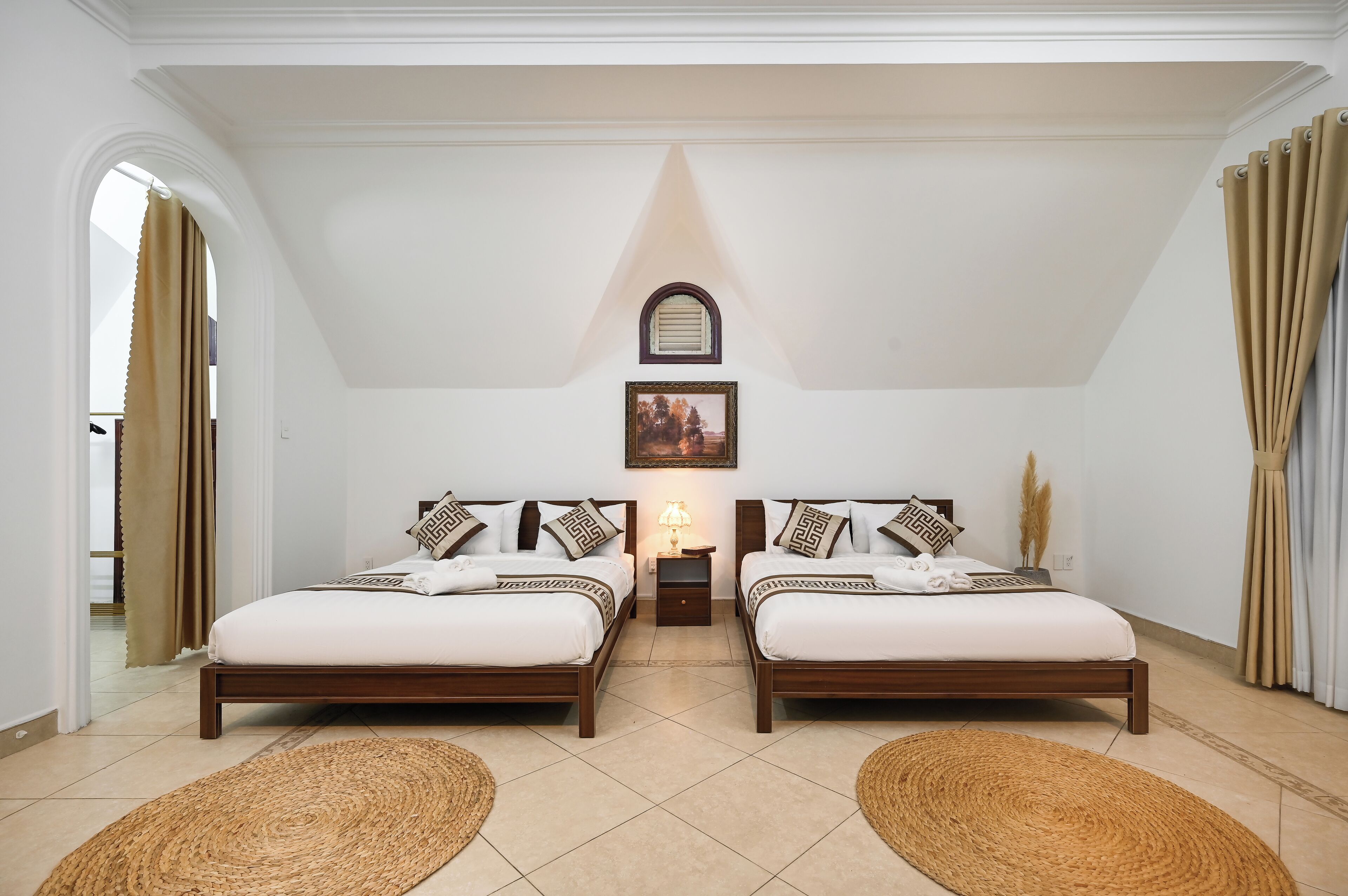 A bedroom with two beds, a nightstand, a lamp, and a framed picture on the wall.
