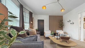 A modern living room with a grey sofa, a wooden coffee table, and a dining area with a wooden table.