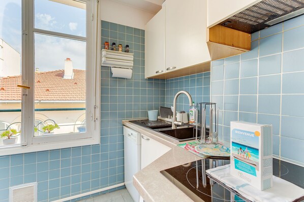 A kitchen with blue tiles, a window, a sink, and a welcome sign.