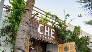 Una entrada de madera con un letrero que dice 'CHE BRASIL' y una estructura de techo de paja.