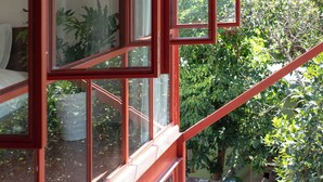 A room with large windows and a view of greenery outside. - Scarlet Pavilion Homestay (Hue)