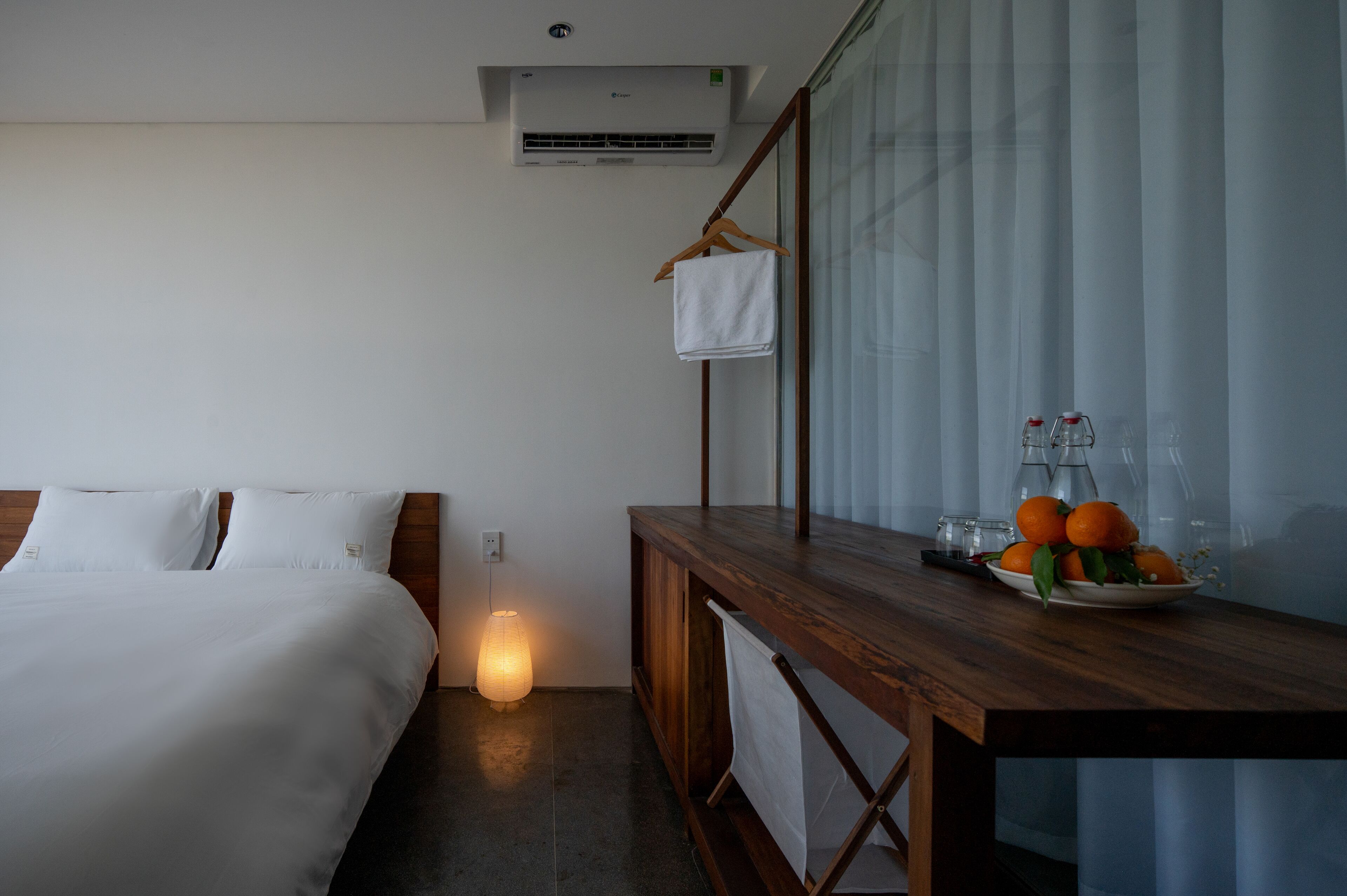 Una habitación de hotel con cama, mesita de noche y un frutero.