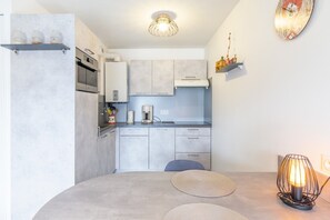 A modern kitchen with a round dining table, a coffee machine, and a pendant light.