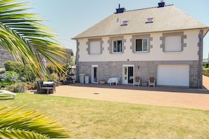 A two-story house with a stone facade, a garage, and a patio area with outdoor furniture.