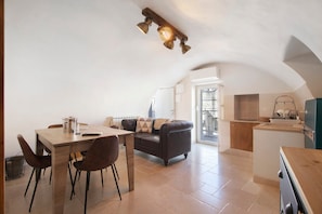 Un espacio habitable compacto con comedor, sofá, kitchenette y vistas al exterior.