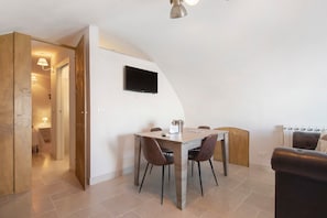 Un comedor con una mesa y sillas, un televisor montado en la pared y un radiador.