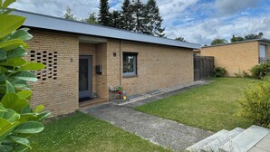 A modern brick building with a flat roof, a small front porch, and a gravel driveway.