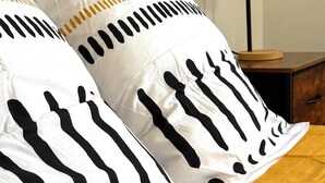 Uma cama com roupa de cama listrada e duas almofadas com padrão preto e branco.