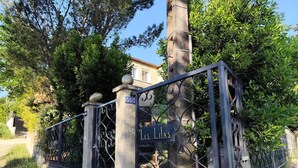 Uma entrada fechada por grades com um portão de metal e uma placa com a inscrição 'LES LILAS'.