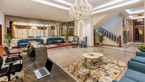 Un hall d’hôtel moderne avec un espace salon, un escalier et un lustre.