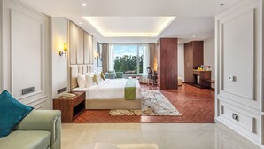 Une chambre d’hôtel moderne dotée d’un grand lit, d’un coin salon avec un canapé, d’un bureau et offrant une vue sur l’extérieur.