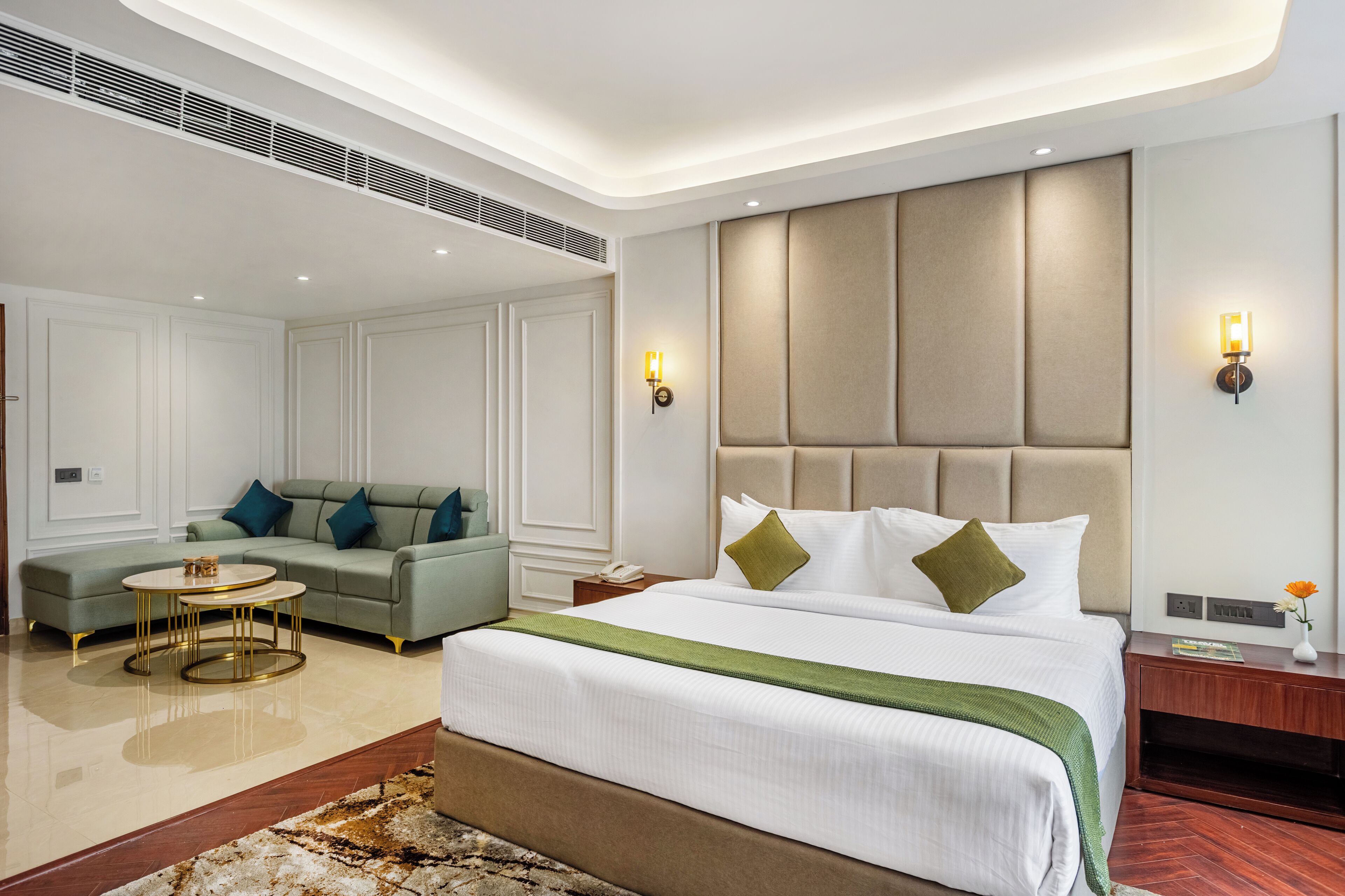 A hotel room with a large bed, a sofa, a small round table, and a nightstand.