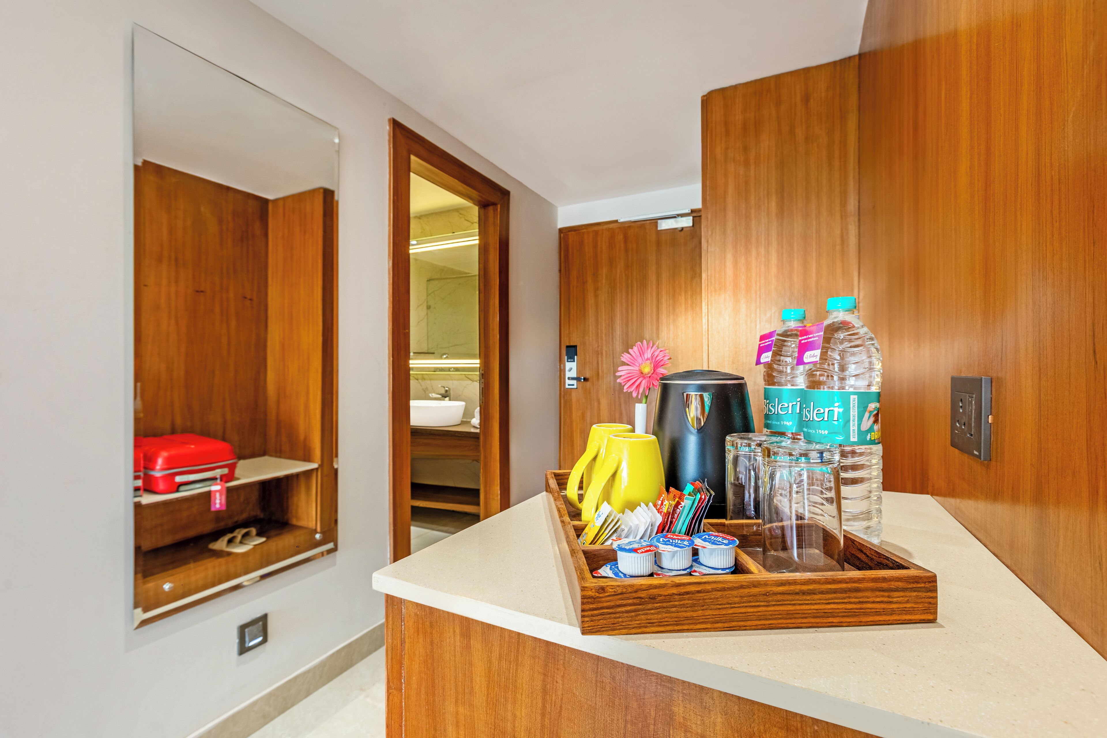Un baño de hotel con armarios de madera, un espejo, un lavamanos y artículos de aseo sobre una encimera.