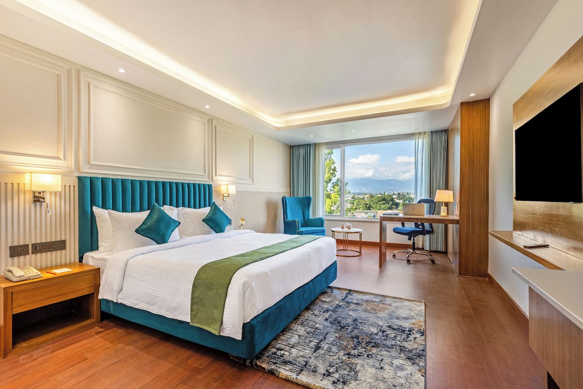Une chambre d’hôtel avec un grand lit, un bureau, une chaise et un téléviseur.