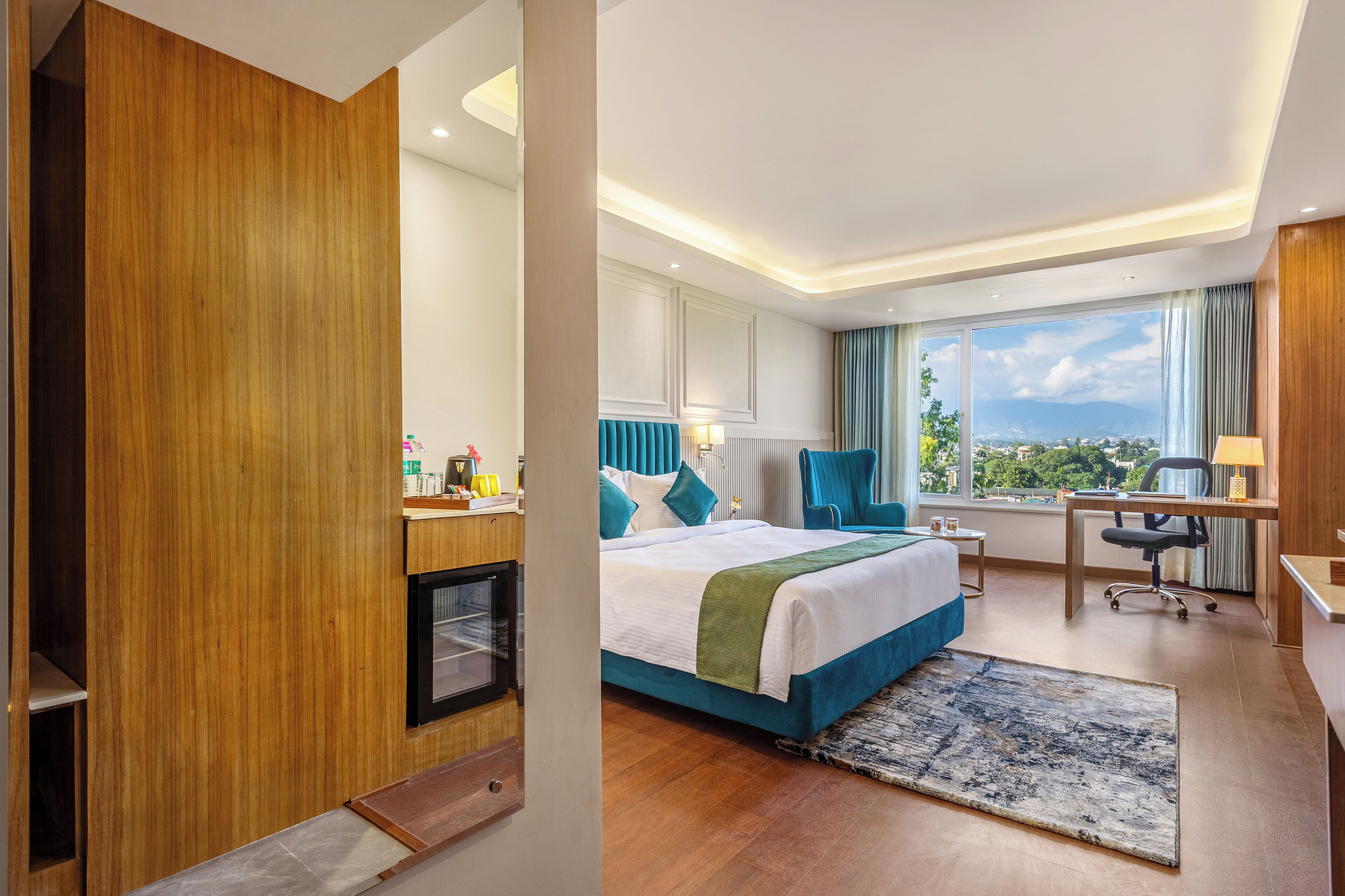 Une chambre d’hôtel avec un lit, un bureau, une chaise et une vue sur la ville.