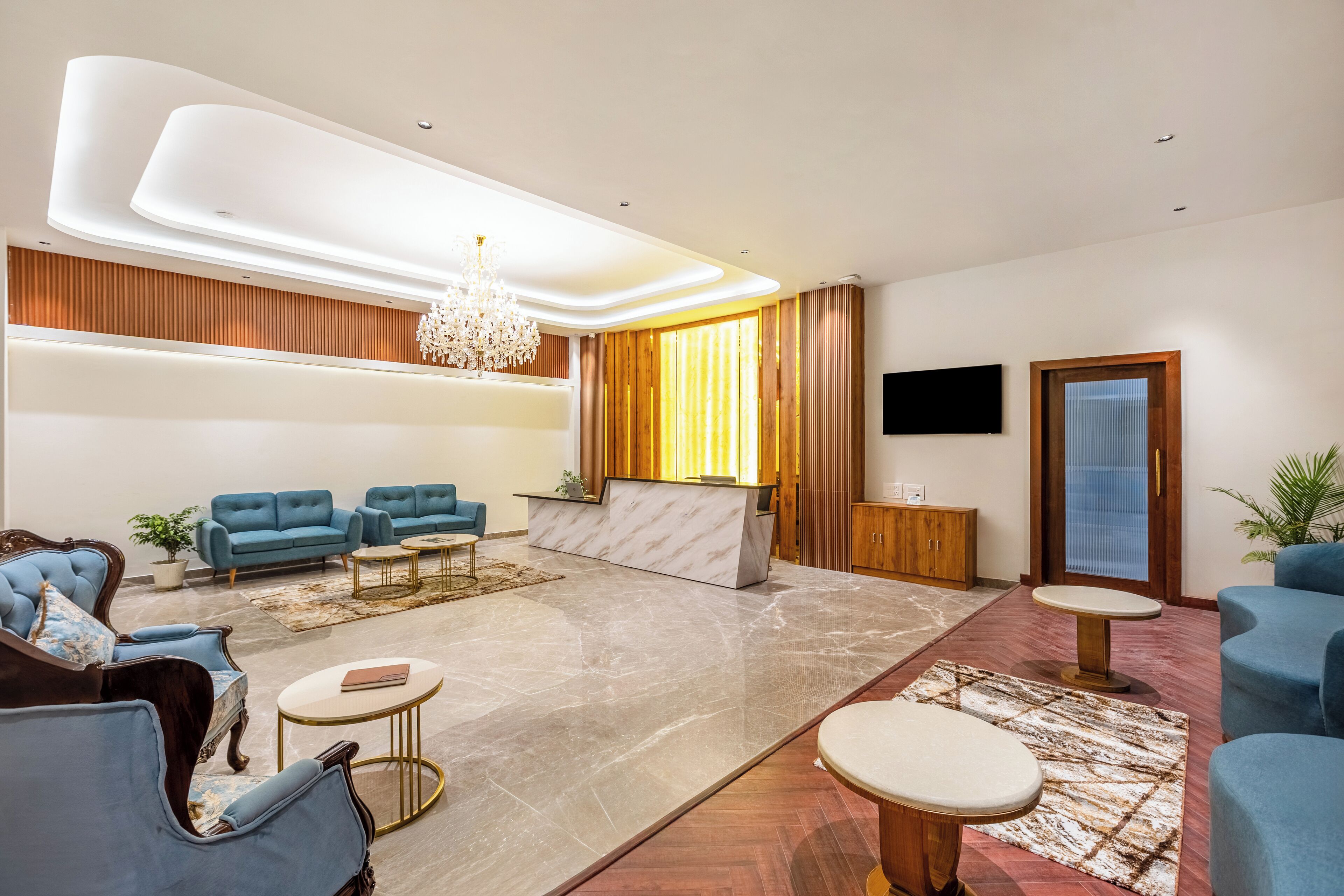 A modern lobby with a reception desk, seating area, and a chandelier.