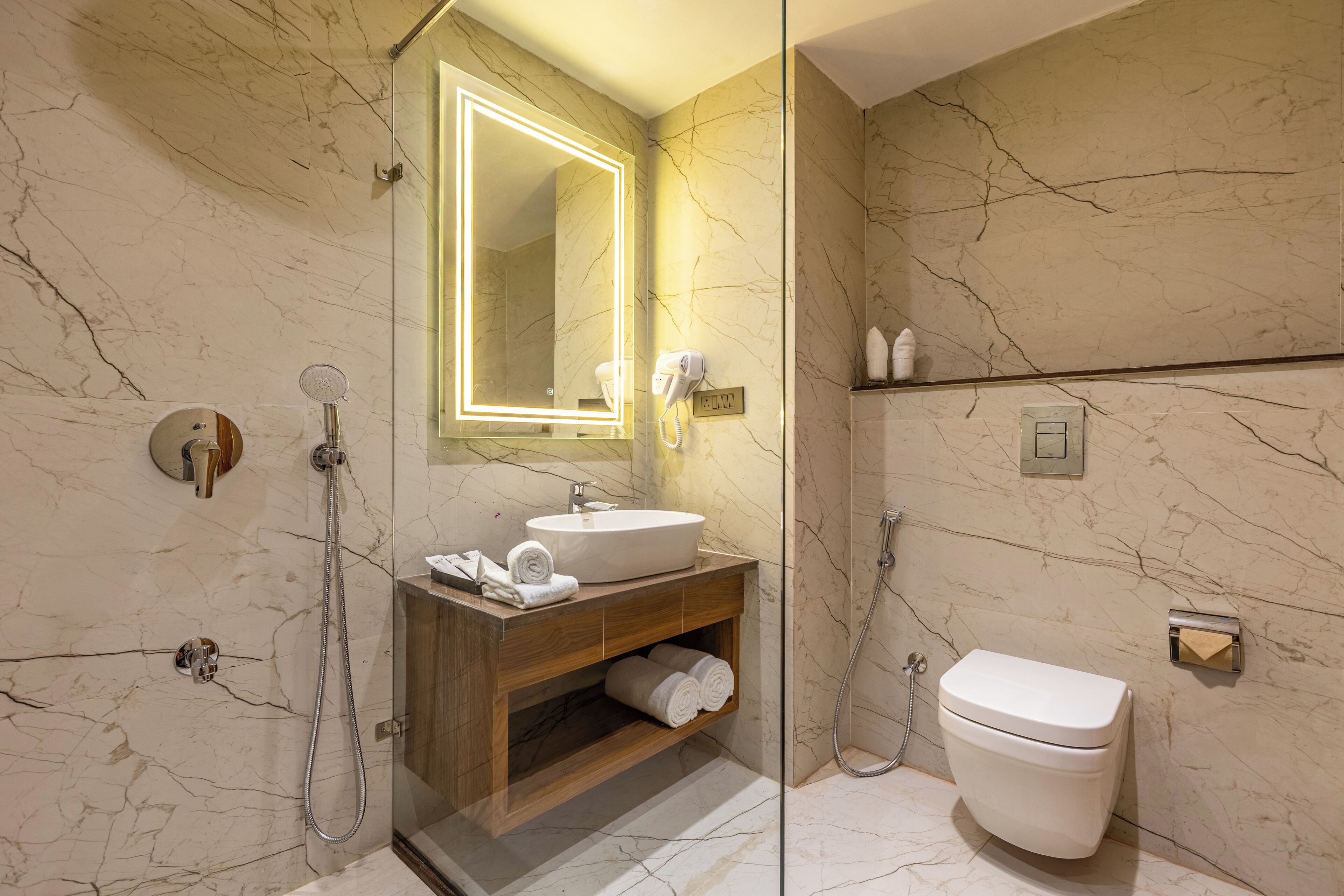 Un baño moderno con tocador de mármol, ducha con cerramiento de vidrio y un inodoro.