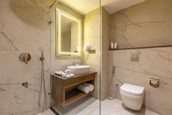 A modern bathroom with a marble vanity, a glass-enclosed shower, and a toilet. - Sterling GK Exotica Dehradun (Dehradun)