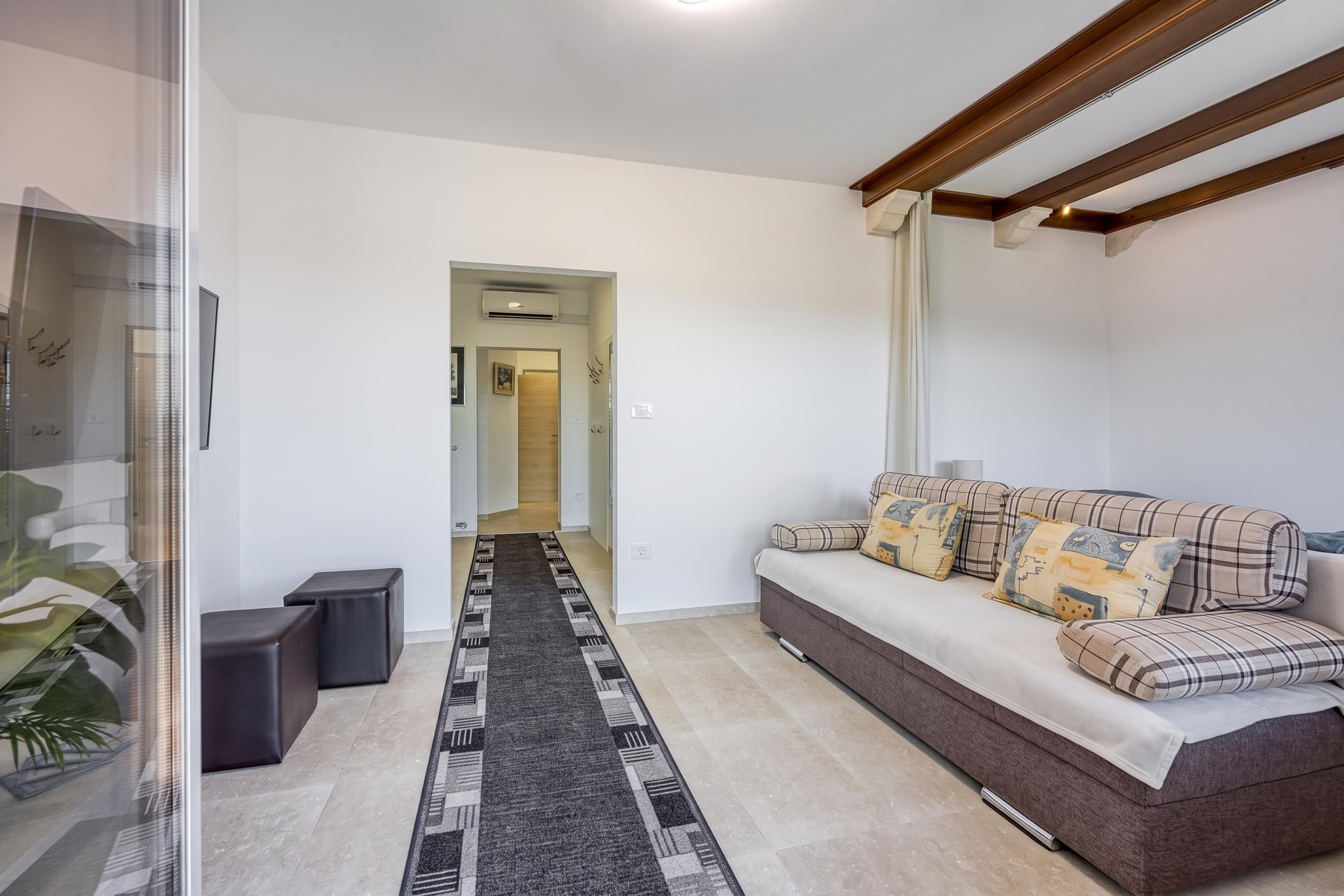 A modern living room with a sofa, a patterned rug, and a glass partition.