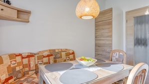 A dining area with a glass table, a woven pendant light, a patterned sofa, and a fruit bowl. - Apt Smode With Panoramic Balcony (Koper)