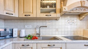 A kitchen with wooden cabinets, a stainless steel sink, and a countertop with a kettle and fresh produce. - Apt Smode With Panoramic Balcony (Koper)