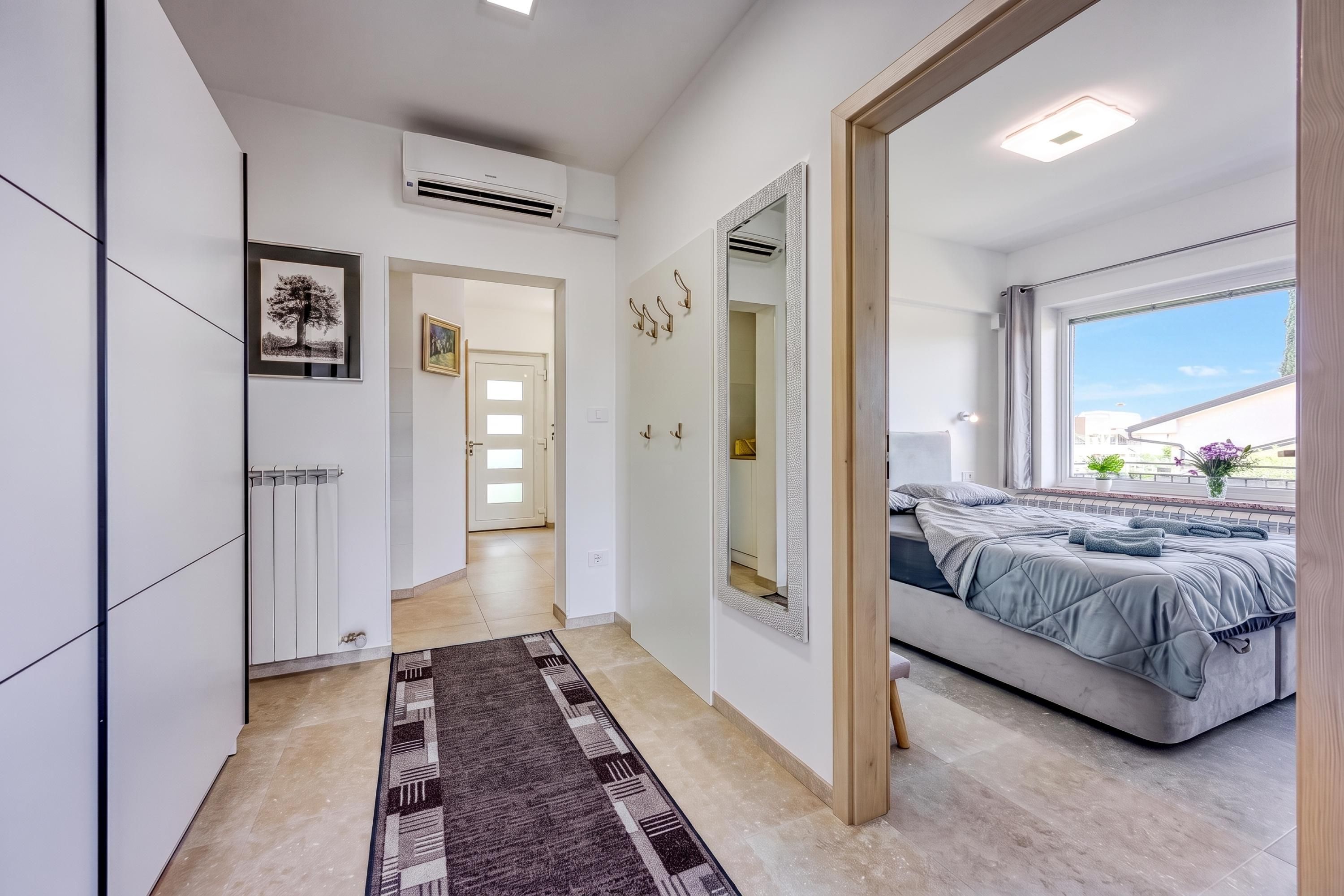 Un dormitorio moderno con cama, un espejo grande y vistas al exterior.
