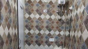 Une salle de bain avec des carreaux décorés, une douche, un lavabo et des toilettes.