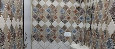 A bathroom with patterned tiles, a shower, a sink, and a toilet.