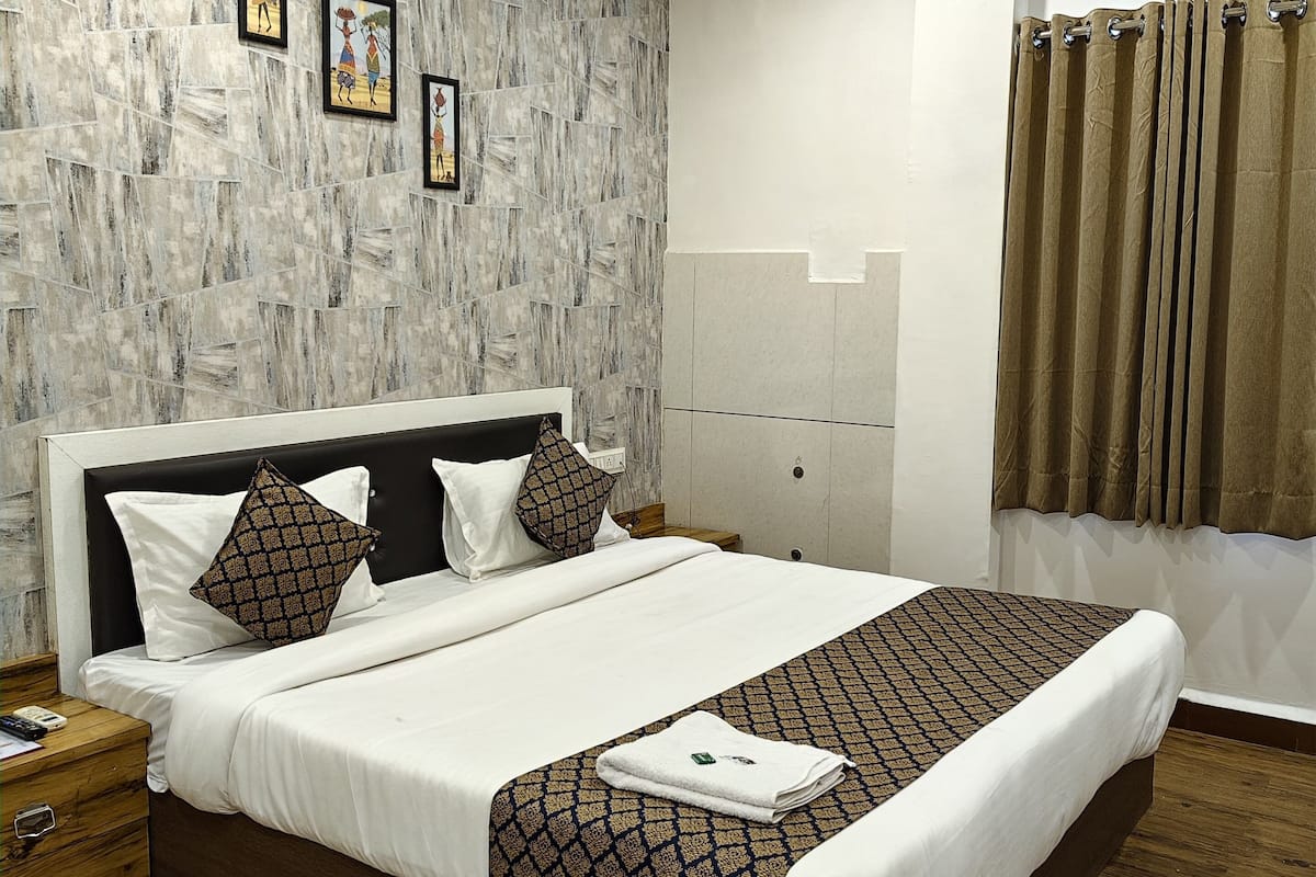 A modern hotel room with a large bed, wooden flooring, a ceiling fan, and a view of the outdoors.