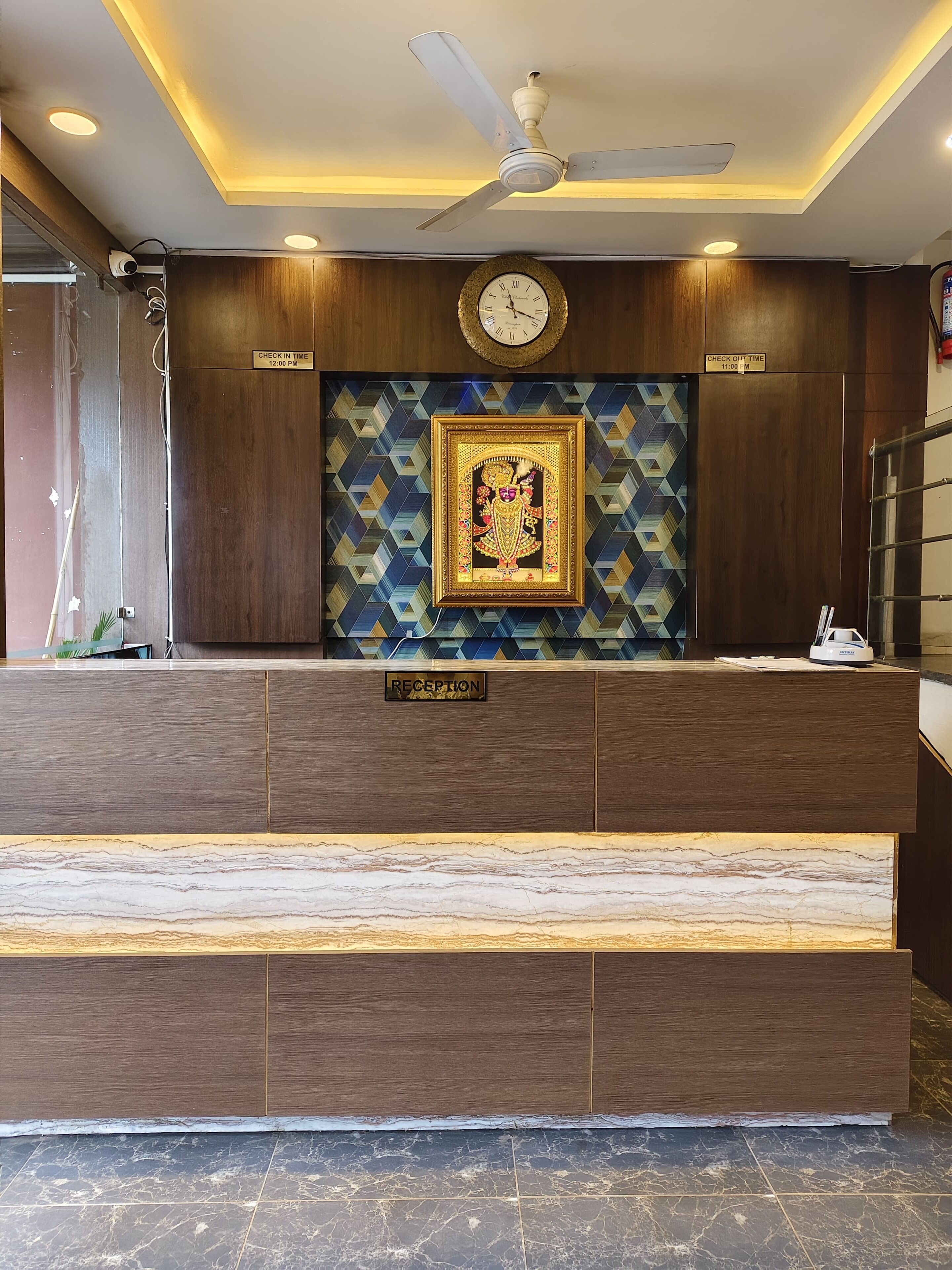 A reception area with a marble counter, a clock, and a framed artwork on the wall.