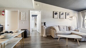 Een moderne woonkamer met een bank, een salontafel en een eethoek met een lange tafel.