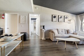Ein modernes Wohnzimmer mit einer Couch, einem Couchtisch und einem Essbereich mit einem langen Tisch.