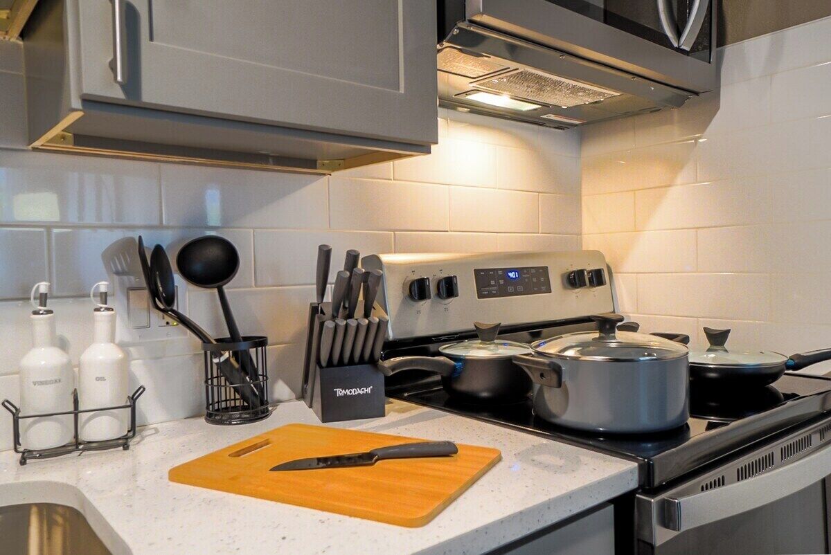 Une cuisine équipée d’une cuisinière, de casseroles, d’une planche à découper et d’ustensiles de cuisine.