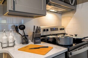 A kitchen with a stove, pots, a cutting board, and utensils.