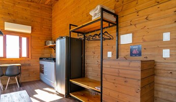 A compact kitchen with a refrigerator, a sink, and a wooden cabinet.