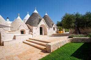 A stone building with multiple conical roofs, a paved courtyard, and a well-maintained lawn. - Villa 'Dimora Dormio' with Private Pool, Wi-Fi, and Air Conditioning (monopoli)